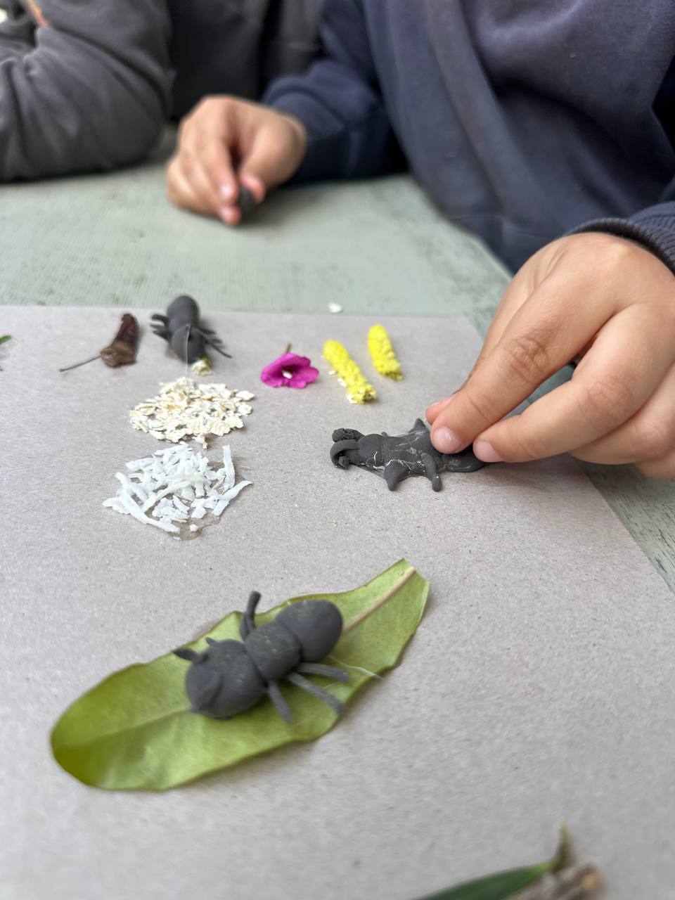 Los niños crean hormigas y hormigueros con arcilla, hojas, ramitas y otros elementos de la naturaleza para el libro colectivo.