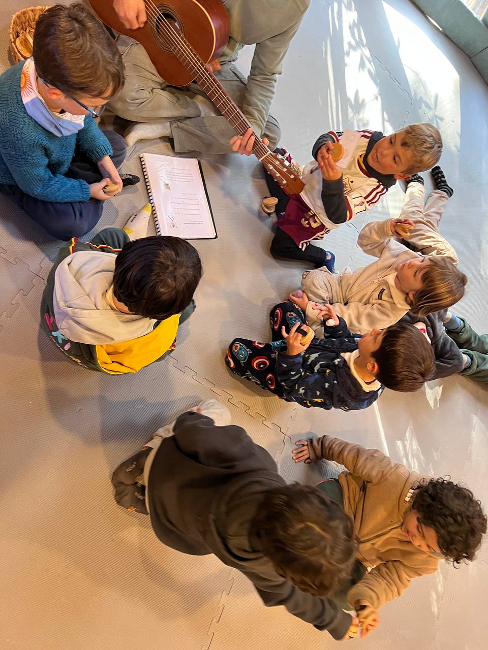 Casa de Niños B: exploración con bloques, clasificación de flashcards de vocabulario y ronda musical con guitarra.