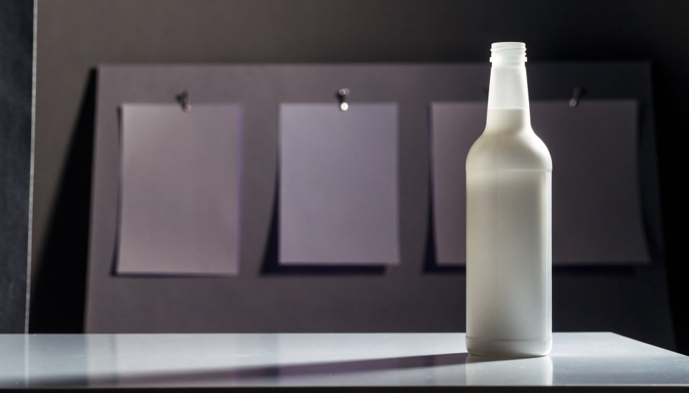 A small product photography setup on a table, one bottle photographed from front, side and three quarter angles, three p