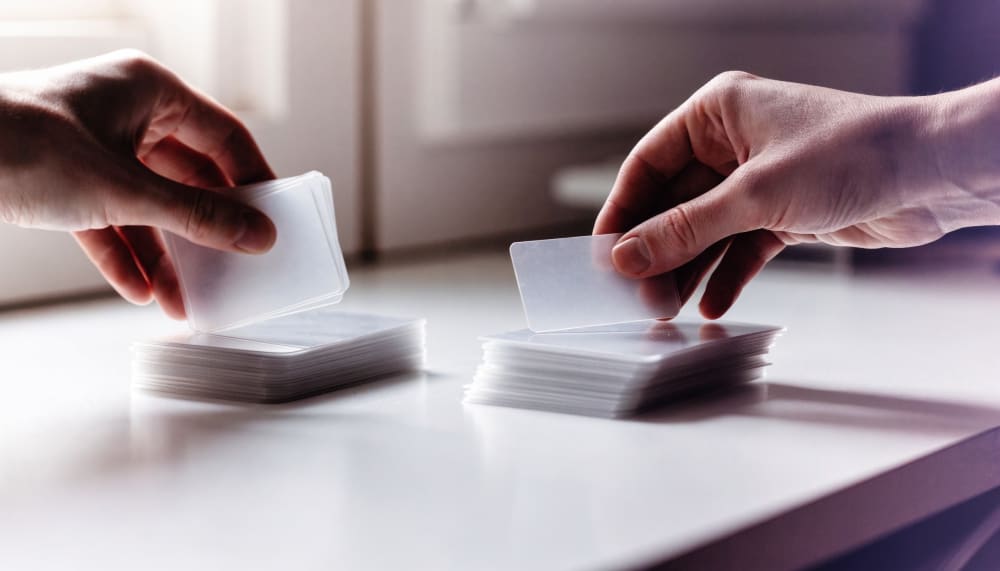 A pair of hands calmly sorting a stack of blank translucent cards into two separate piles on a bright uncluttered desk,