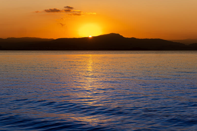 Uma linha de luz une céu, montanha e mar. Um instante efêmero em que cor, forma e reflexão se encontram para revelar a beleza da simplicidade