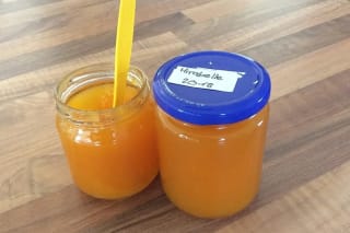 Glas mit tiefroter Mirabellenmarmelade und frischen Mirabellen daneben