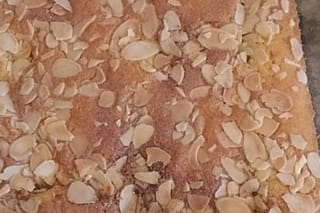 Goldbrauner Blitzkuchen mit knusprigen Mandelsplittern, frisch aus dem Ofen auf einem Backblech