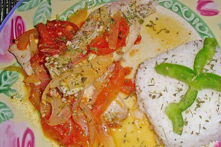 Gebratene Corvina Filets auf einem Bett aus Tomaten, Zwiebeln und Ají, garniert mit Zitronenscheiben und Oregano