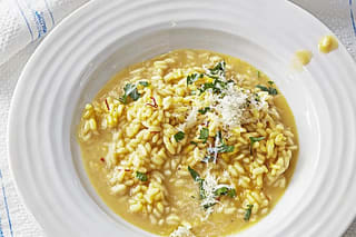 Cremiges Risotto alla Milanese mit goldener Safranfarbe und geriebenem Grana Padano in einem tiefen Teller