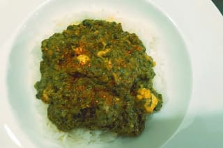 Cremiges Chicken Palak auf fluffigem Basmatireis, garniert mit rotem Chili