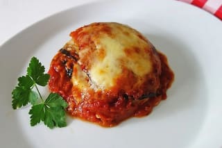 Schichtweise angeordnete Auberginen, Tomatensauce, geschmolzener Mozzarella und Parmesan in einer Auflaufform, goldbraun überbacken