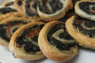 Knusprige Spinat‑Blätterteig‑Schnecken, goldbraun aus dem Ofen, auf einem Backblech angerichtet.