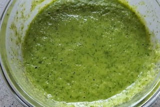Grüne Mojo Verde Sauce in einer Schale, garniert mit Korianderblättern, neben geräuchertem Ziegenkäse und kleinen Kartoffeln