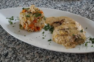 Goldbraun überbackenes Ofenschnitzel mit cremiger Sahnesoße, daneben rustikale Spätzle und frischer grüner Salat