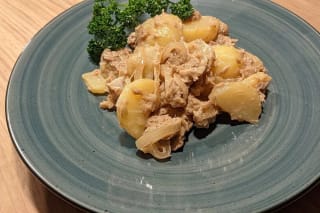 Kartoffelsalat mit Thunfisch, garniert mit Sesam und frischem Pfeffer auf einem rustikalen Holztisch