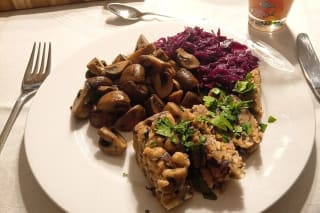 Aufgeschnittene vegane Serviettenknödel in Scheiben, bestreut mit frischer Petersilie auf einem rustikalen Holzbrett