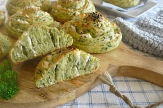 Frisch gebackene Spinat‑Käse‑Schnecken mit goldbrauner Kruste, seitlich aufgebrochen, die cremige Käsefüllung sichtbar