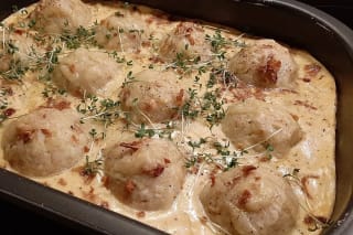 Knödel-Sauerkraut-Auflauf in einer Auflaufform, oben knusprig gebackener Käse, servierfertig auf rustikalem Holztisch