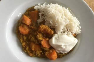 Dampfendes rotes Linsen‑Süßkartoffel‑Curry in einer Schüssel, garniert mit frischem Koriander