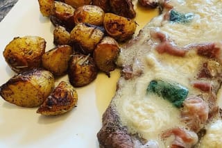 Goldbraun gebratene Kalbsschnitzel Saltimbocca mit schmelzender Buttersoße auf Holzbrett