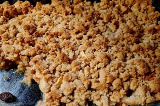 Goldbrauner Apfel-Crumble mit knusprigem Streusel, daneben ein Klecks Vanilleeis