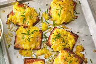 Knuspriger Rösti-Auflauf mit goldbrauner Käsekruste und daneben liegenden Fleischscheiben auf einem Backblech
