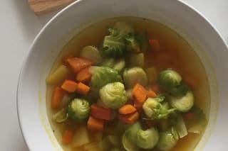 Rosenkohl-Kürbis-Eintopf in einem rustikalen Topf, garniert mit frischer Petersilie