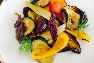 Grillgemüse Salat auf Holzbrett mit Senfdressing, garniert mit gerösteten Kürbiskernen