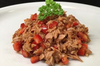 Goldbraun gebackene spanische Thunfisch‑Empanadas auf einem Holzbrett, daneben ein Zitronenviertel