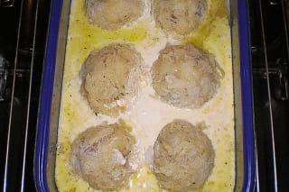Knusprig gebackene Sauerkrautknödel in weißer Sauce, daneben ein Klecks Sahne und frische Kräuter