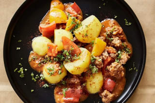 Bunte Paprika‑Hack‑Pfanne mit goldbraunen Kartoffelwürfeln und frischer Petersilie auf rustikalem Holzbrett