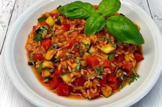 Bunte Reispfanne mit Paprika, Zucchini und frischem Basilikum, serviert in einer Pfanne