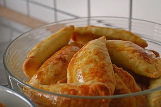 Selbstgemachte vegetarische Empanadas mit goldbrauner Kruste und bunter Gemüsefüllung auf einem Holzbrett