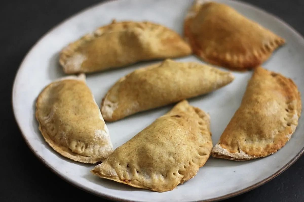 Goldbraun gebackene vegane Empanadas auf Backpapier, gefüllt mit Sojagranulat und Gemüse
