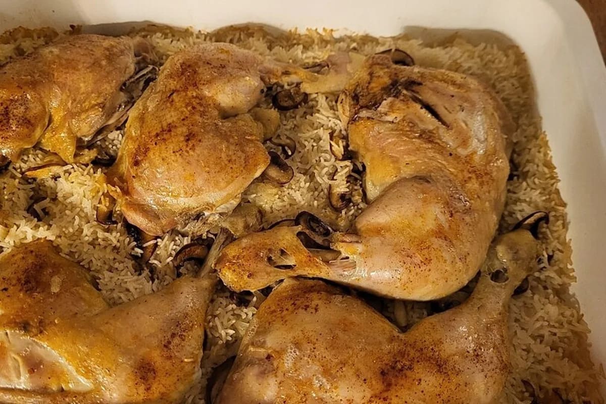 Goldbraune Mazedonische Reispfanne mit Hähnchenschenkeln, serviert auf einem rustikalen Teller