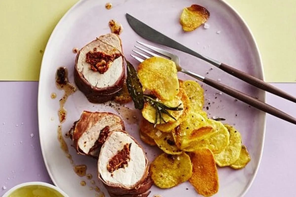 Goldbraun gebackenes Schweinefilet im Parmaschinken, umgeben von rotem Pesto und Rosmarinkartoffeln