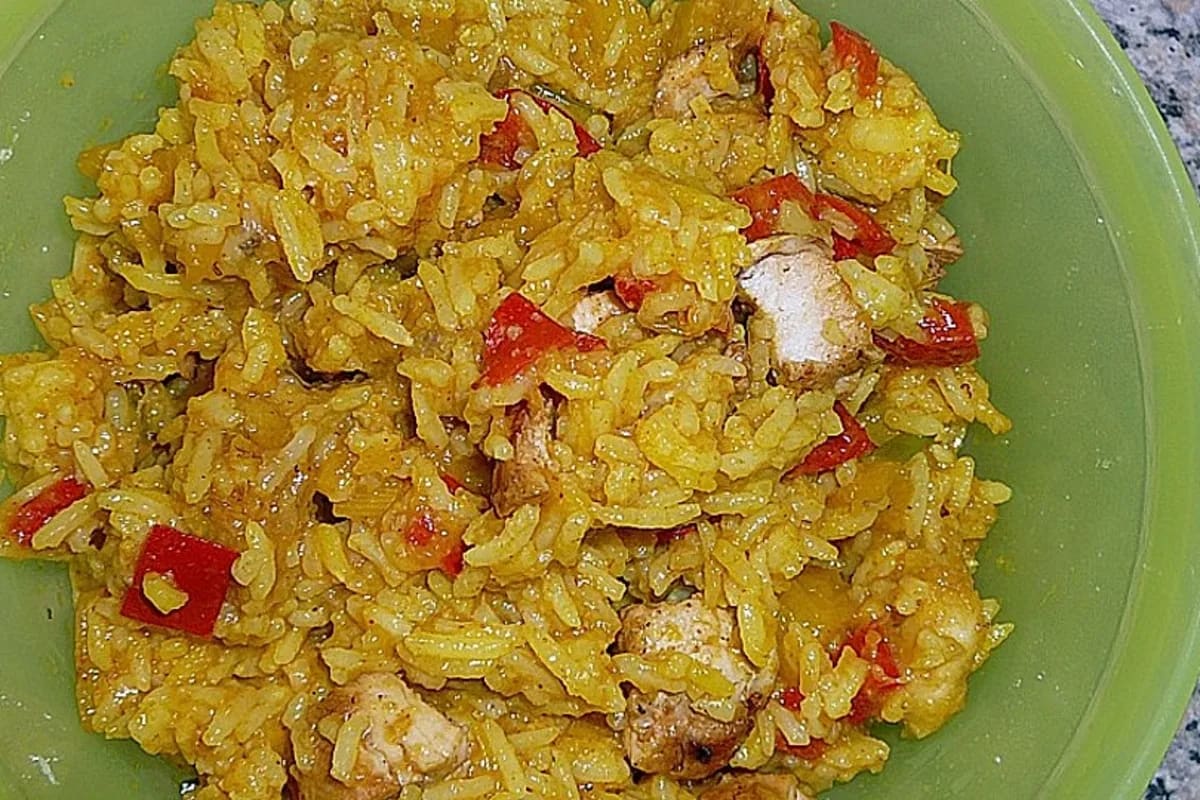 Bunter Reissalat mit goldgelbem Kurkuma-Reis, grünen Paprikastreifen, karamellisierten Bananen und Mangowürfeln, garniert mit Zitronenscheibe und Chili-Flocken