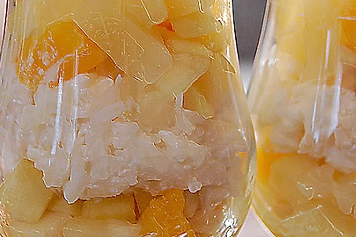 Bunter Reissalat mit Joghurt, Mango, Erdbeeren und Minzblättern in einer weißen Schüssel