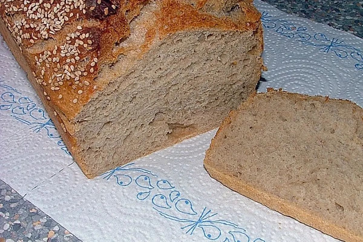 Goldbraunes Bauernbrot mit Sonnenblumenkernen, aus dem Brotbackautomaten entnommen, auf Holzbrett geschnitten