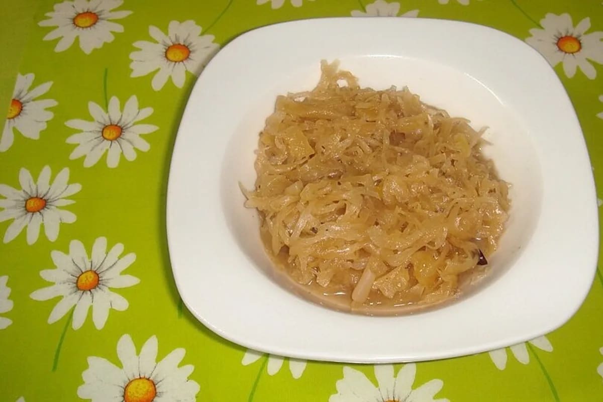 Dampfend heißes böhmisches Sauerkraut im Topf mit goldbraunen Speckwürfeln