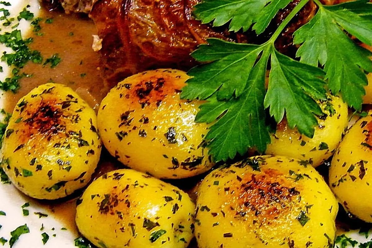 Goldbraun gebratenes Wiener Schnitzel mit grünen Petersilienkartoffeln auf einem rustikalen Holzbrett