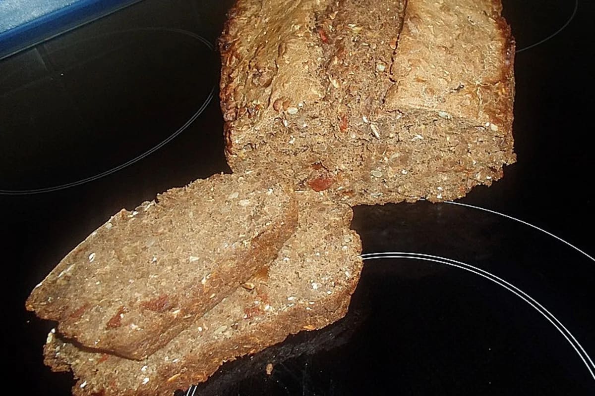 Goldbraunes Körnerbrot mit knuspriger Kruste, in Scheiben geschnitten, auf Holzbrett serviert