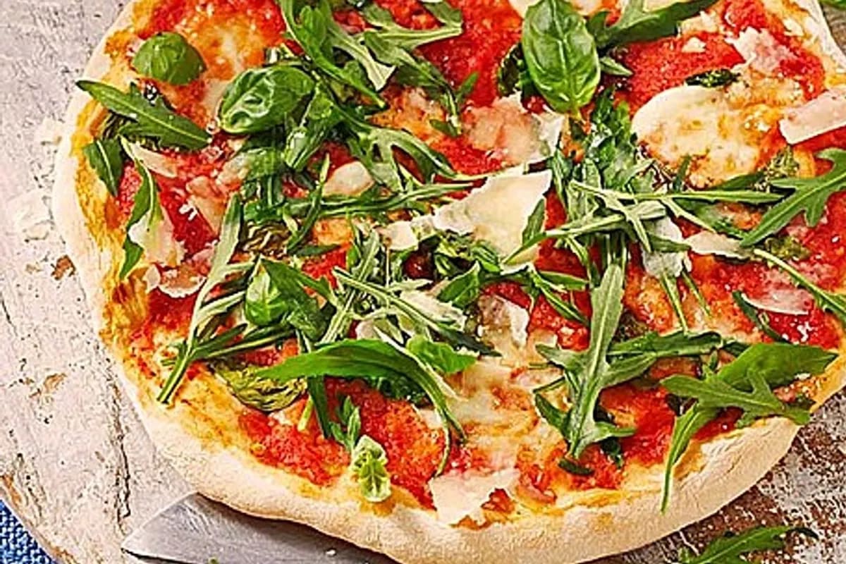 Frischer, runder Pizzaboden mit goldbraunem Rand auf einem Backstein