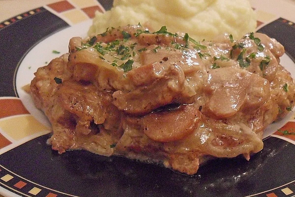 Goldbraune Schnitzel in cremiger Pilzsauce, daneben Nudeln und frischer grüner Salat