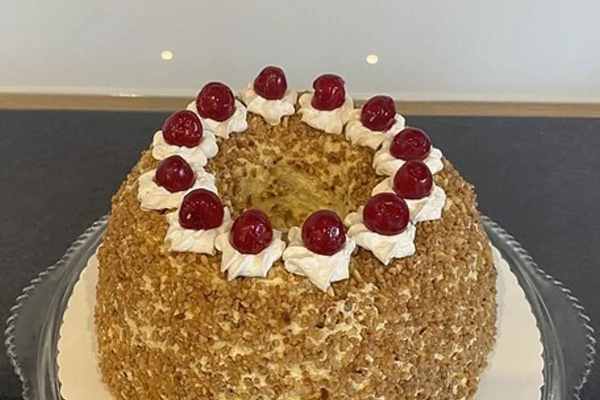 Ein frisch geschichteter Frankfurter Kranz mit knusprigem Krokant, roter Himbeerkonfitüre und glatter Buttercreme