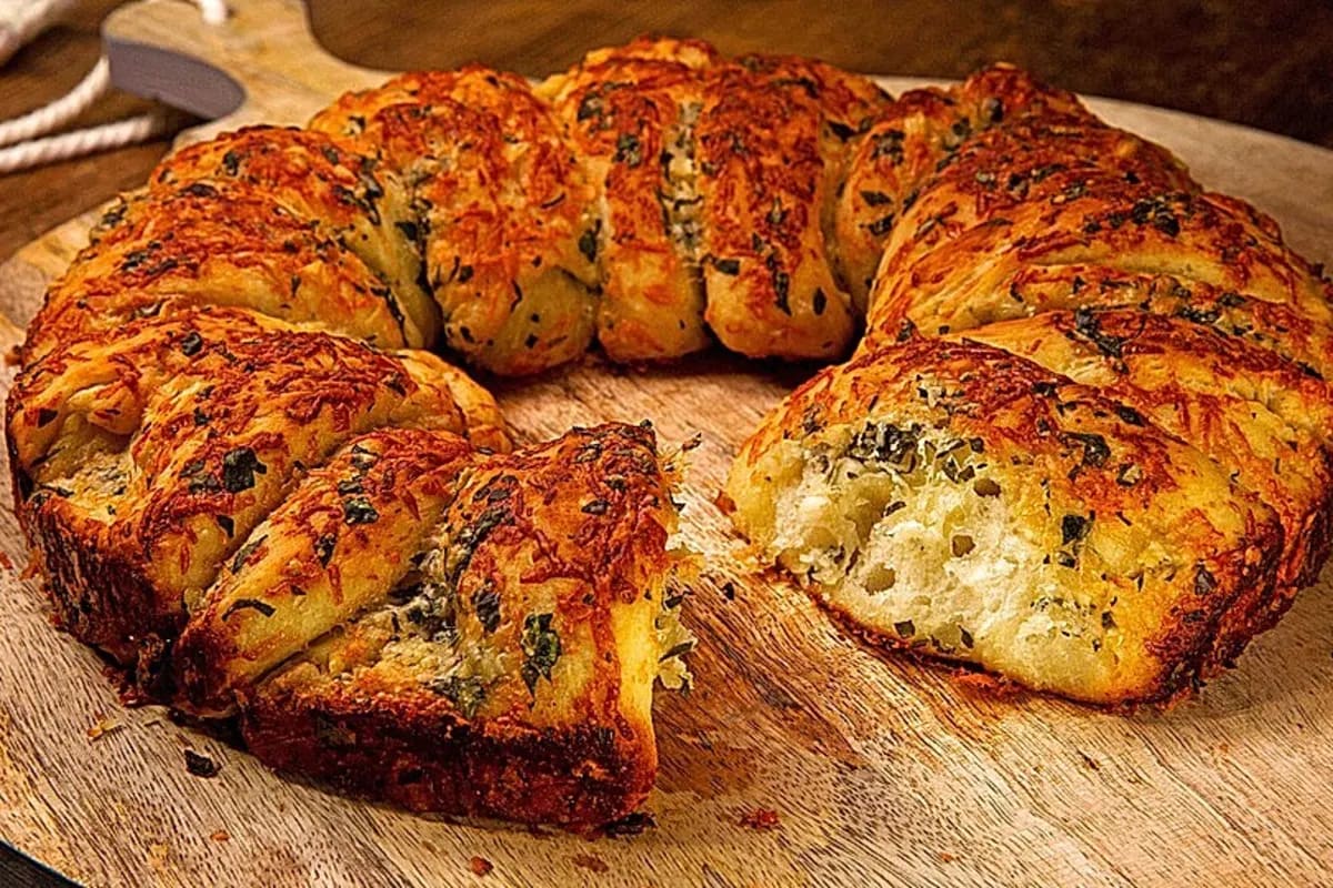 Frisch gebackenes, goldbraunes Knoblauchbrot in Scheiben, mit geschmolzenem Käse und Kräutern bedeckt