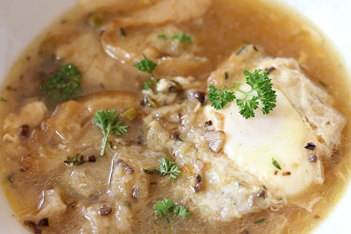 Schüssel mit spanischer Knoblauchsuppe, knusprigem Brot und pochiertem Ei, garniert mit Petersilie