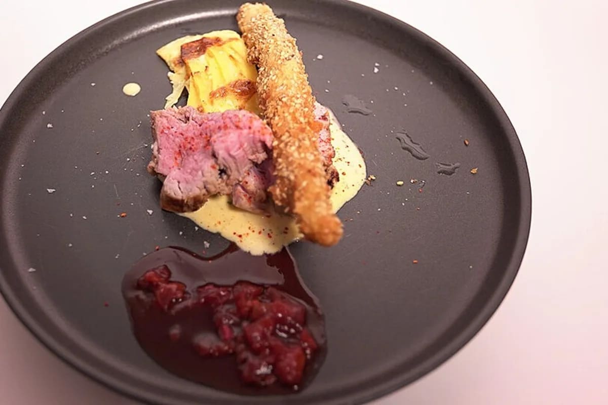 Cremiges Kartoffelgratin mit grünem Spargel und knusprigen Spargelstreifen, serviert auf einem rustikalen Holzbrett