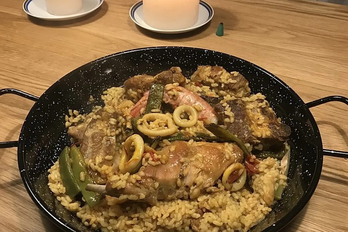 Paella mit Kaninchen, Safranreis und Garnelen in einer traditionellen Paellapfanne