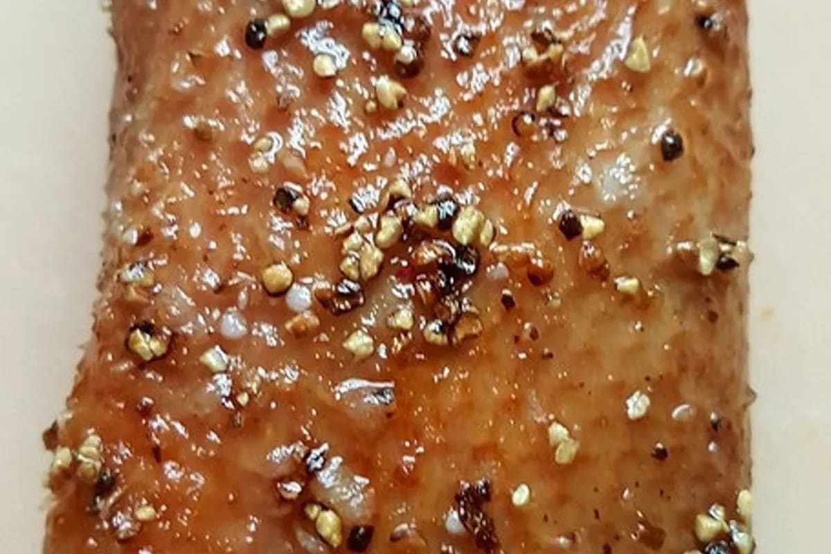 Goldbraun glasierte Entenbrust mit knuspriger Haut, daneben karamellisierte Zwiebeln auf rustikalem Holzbrett