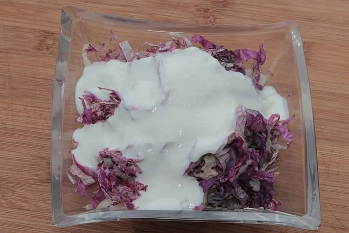 Bunter Chinakohlsalat mit goldbraunen Sesamsamen und cremigem Dressing auf Holzbrett