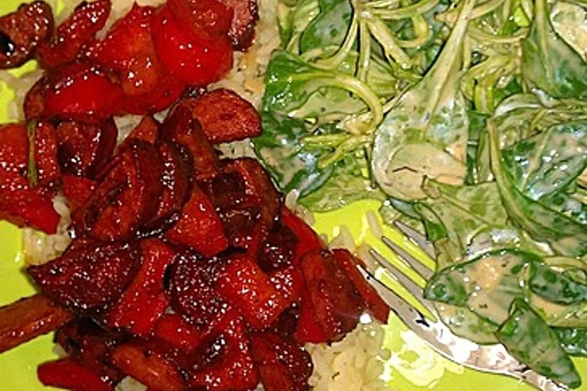 Pfanne mit roter Paprika, goldbraunen Cabanossi‑Scheiben und fluffigem Reis, alles auf dem Herd