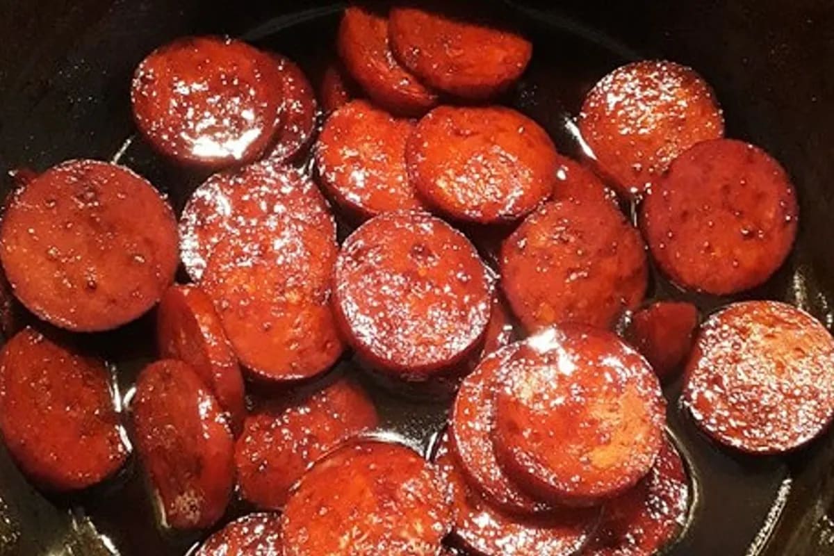 Scheiben von gebratener Chorizo liegen in einer glänzenden Rotweinsauce, daneben ein Stück knuspriges Ciabatta