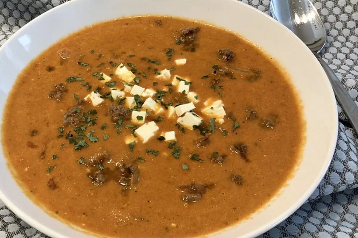 Cremige Paprikasuppe mit zerbröseltem Feta und frischen Schnittlauchröllchen, serviert in einer tiefen Schüssel